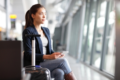 Woman sitting next to suitcase holding cellphone