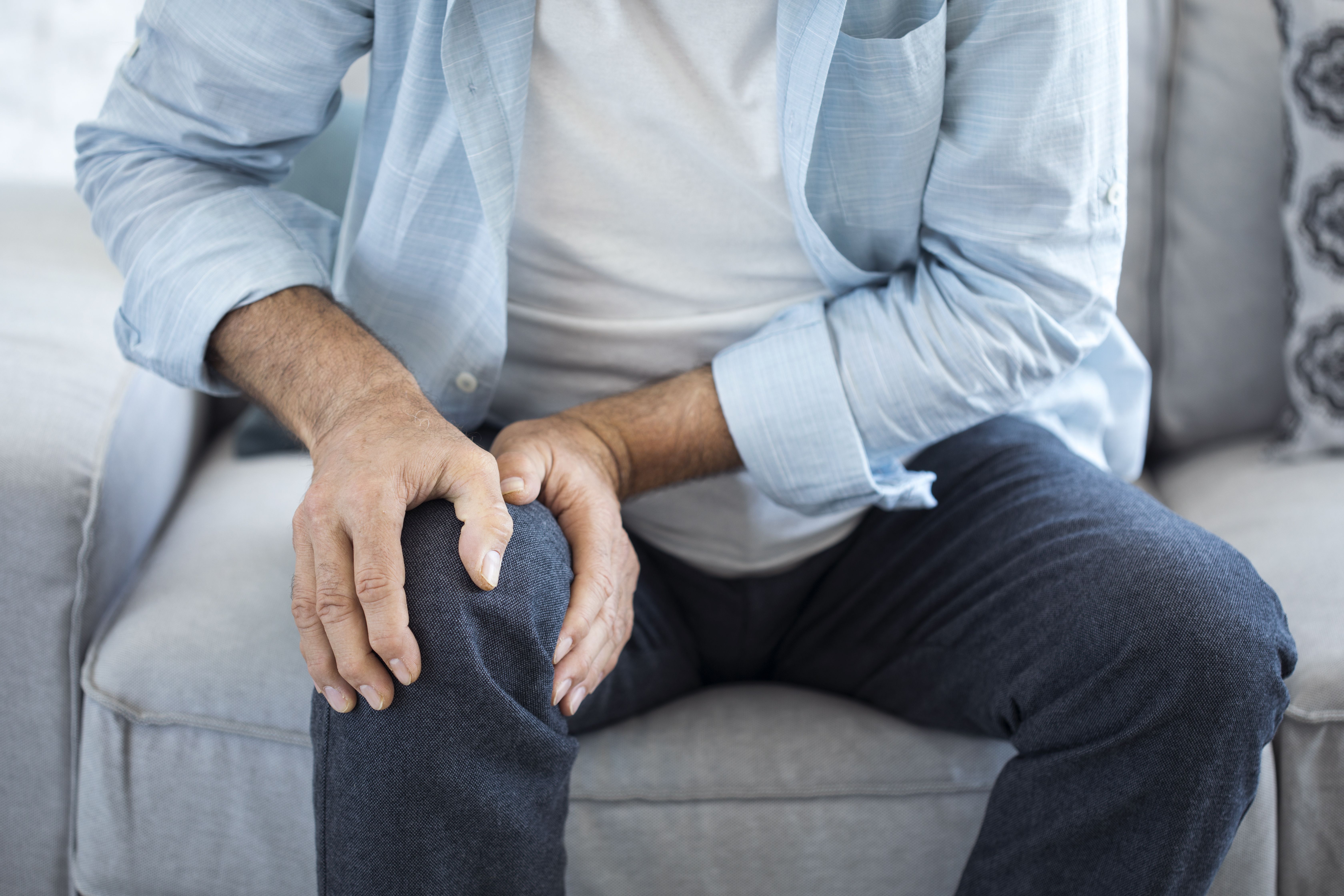 man with hands cupped around right knee